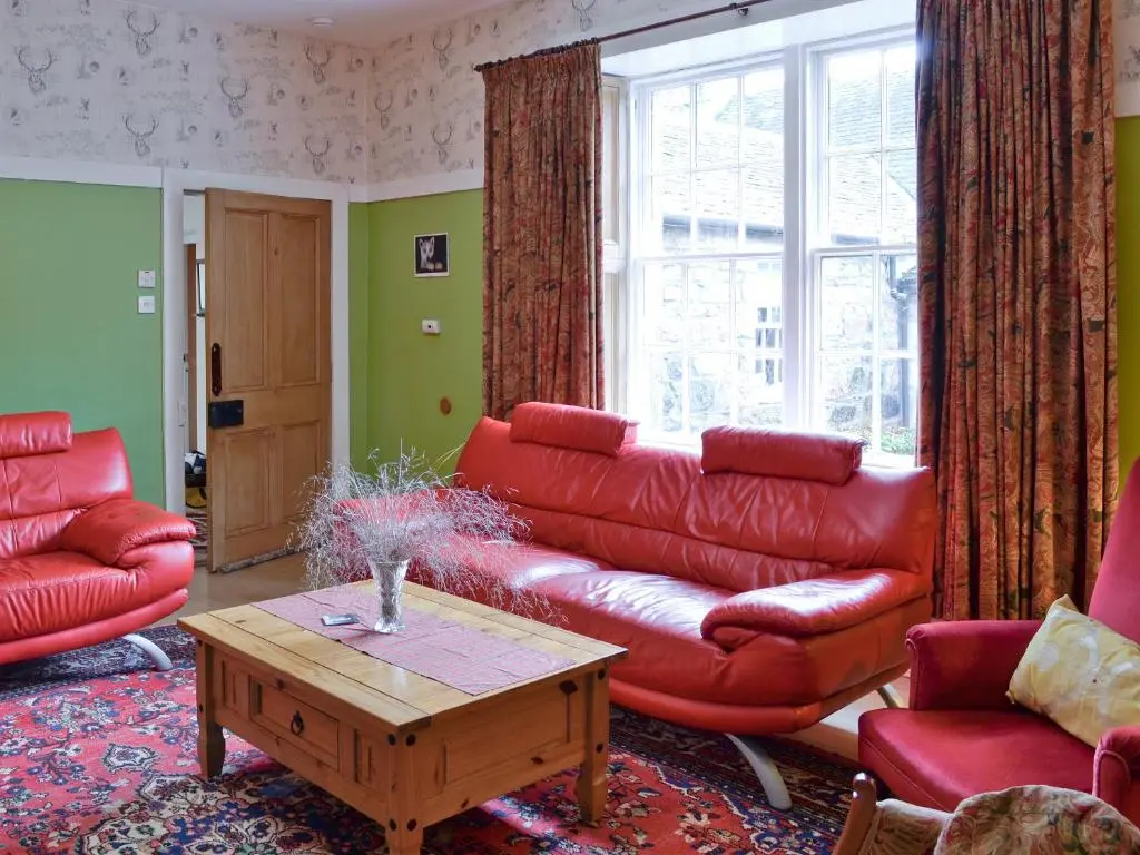 a living room with a red couch and a table at The Mews in Insch