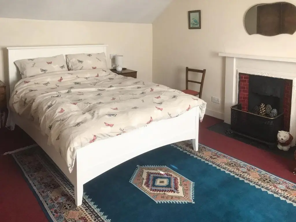 a white bed in a room with a fireplace at The Mews in Insch