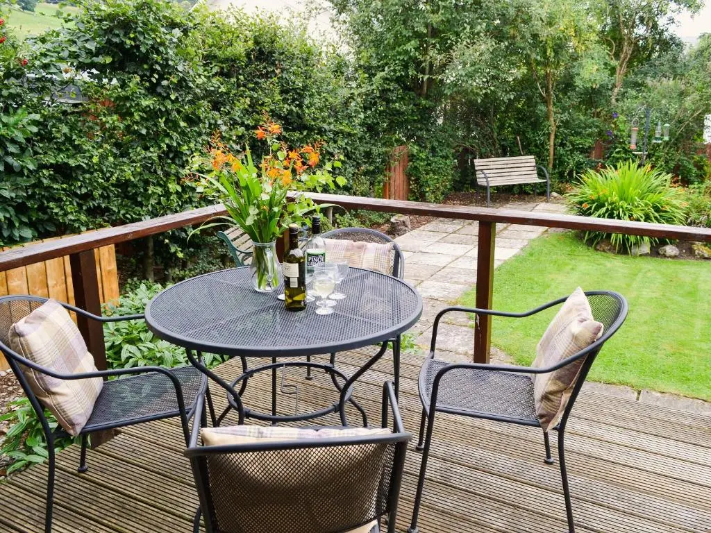 a table with chairs and a vase of flowers on a deck at Wee Ben in Bridge of Tilt