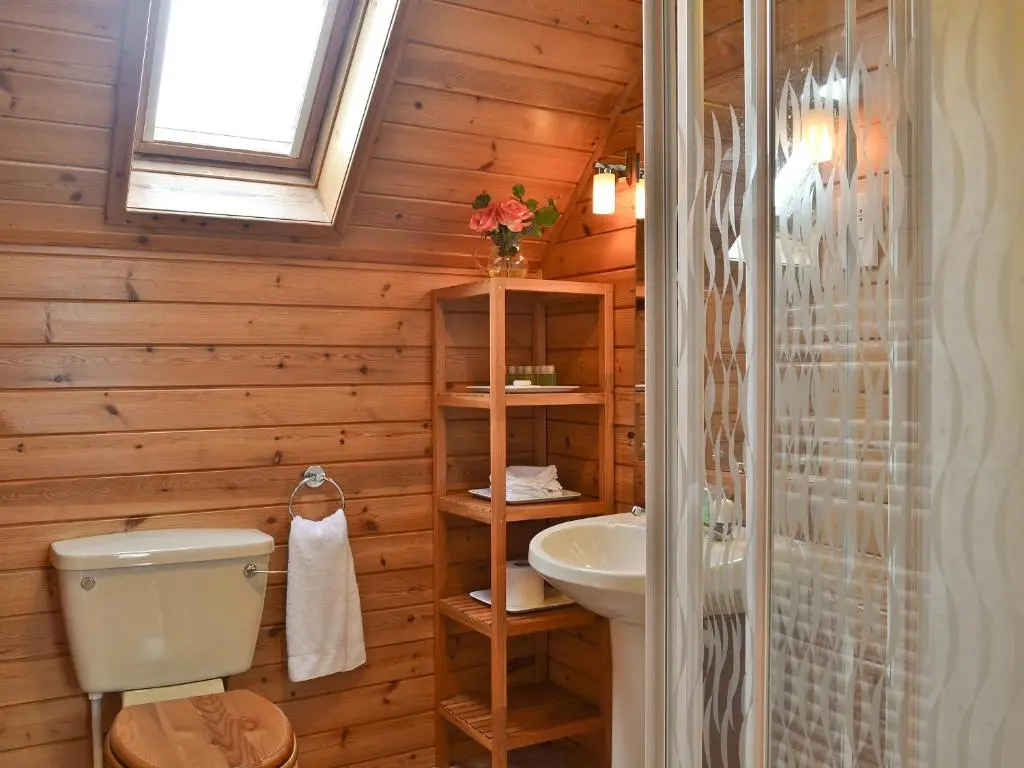 a bathroom with wooden walls and a toilet and a sink at Wee Ben in Bridge of Tilt