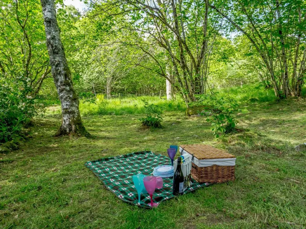 a picnic table with two chairs and a basket on the grass at Glen View Of Enrick House in Bearnock