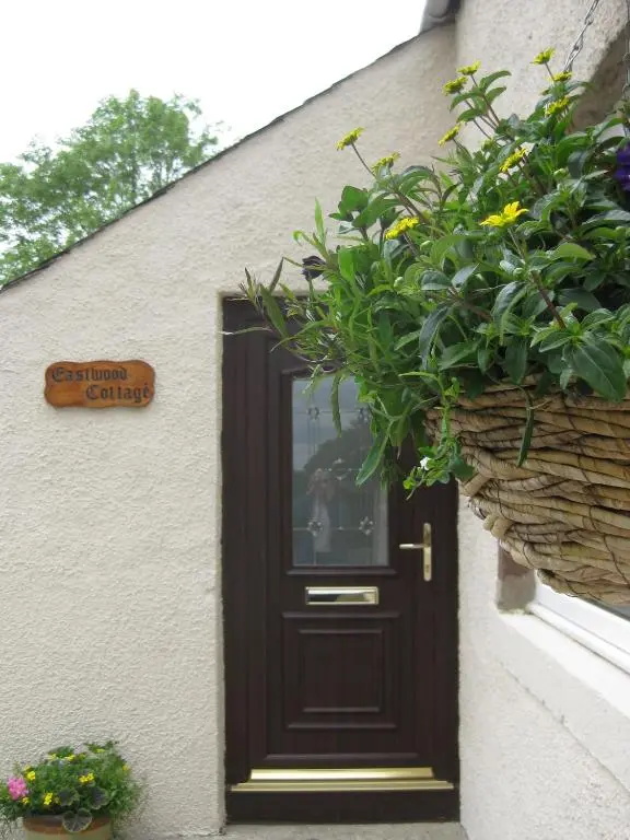 a door to a building with flowers and plants at Eastwood Cottage in Turriff
