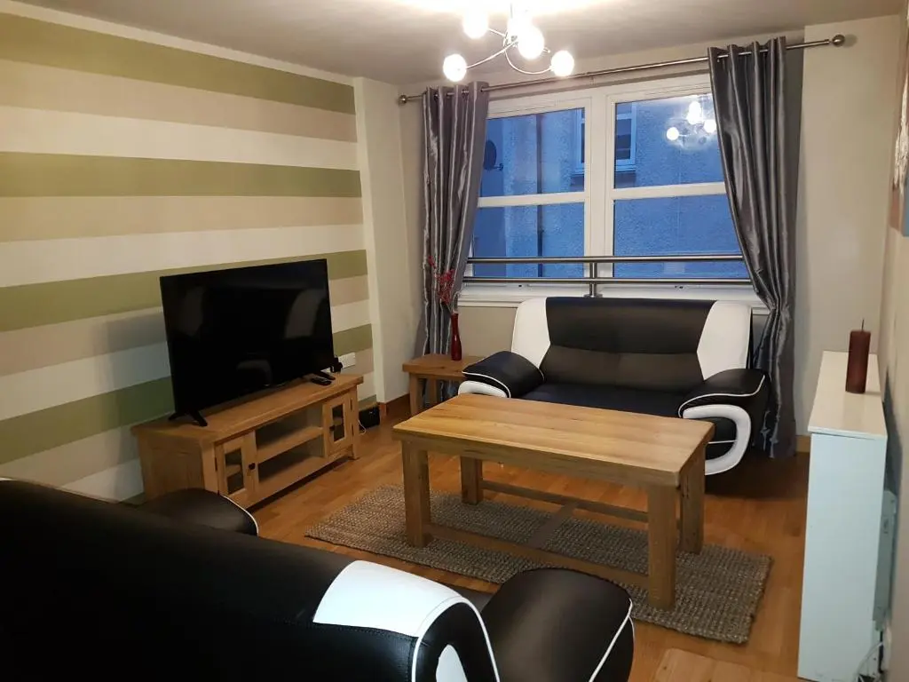 a living room with a couch and a tv at Lascala City Apartment in Inverness