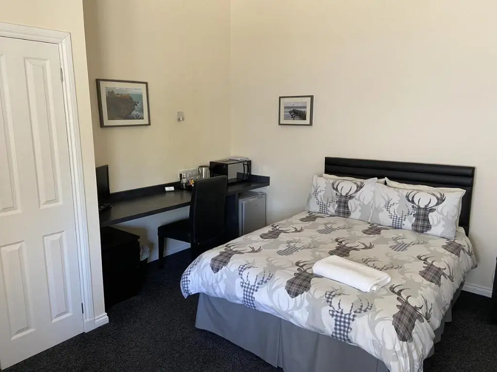 a bedroom with a bed and a desk with a computer at Ivy Cottage-Serviced accommodation in Dyce