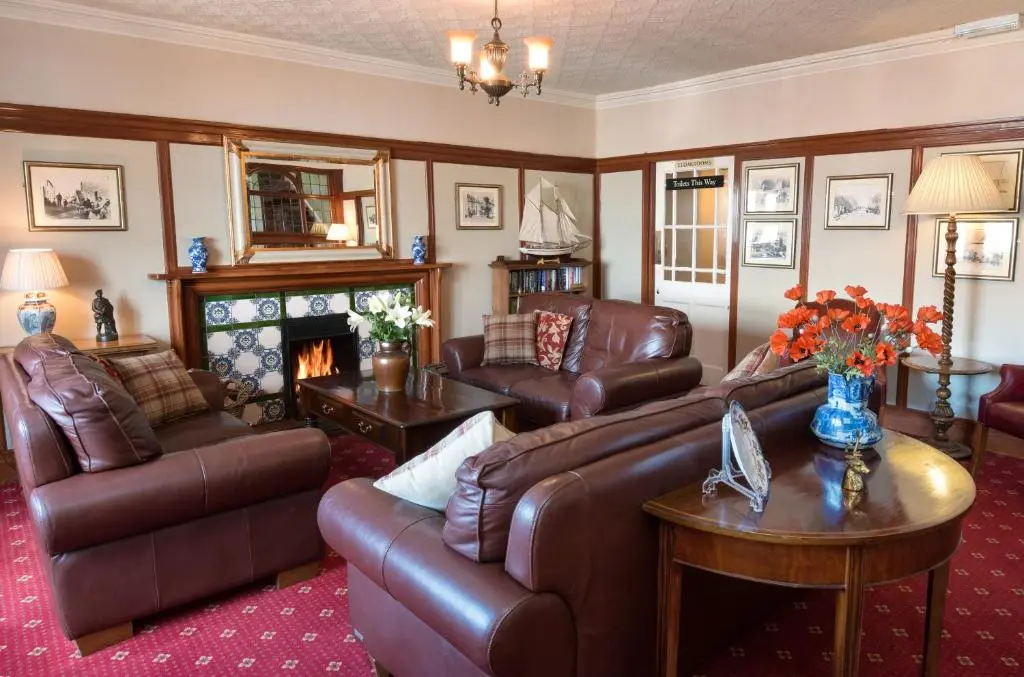 a living room with leather furniture and a fireplace at The Royal Hotel Cromarty in Cromarty
