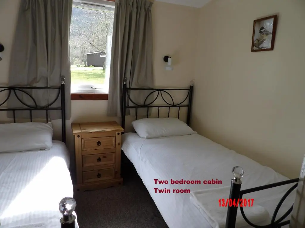 two beds in a room with a window at Forest Glen Holiday Park in Invermoriston