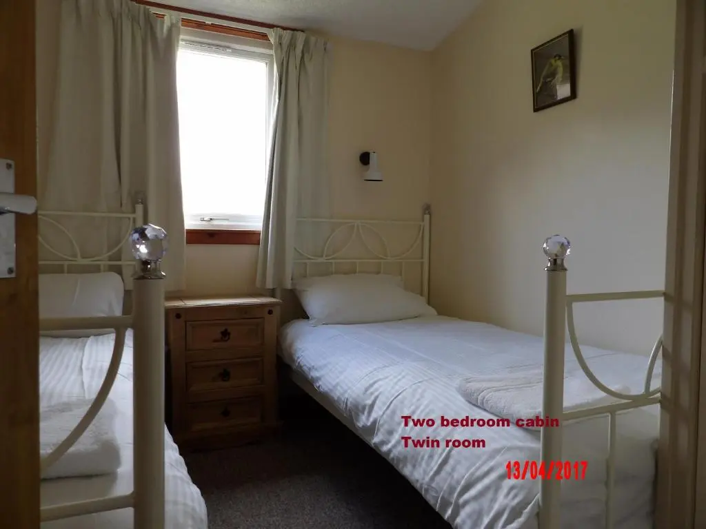 a bedroom with two bunk beds and a window at Forest Glen Holiday Park in Invermoriston