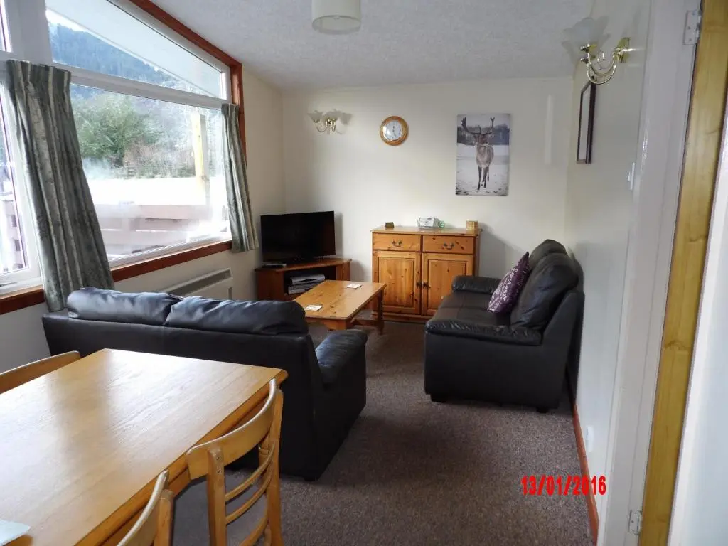 a living room with two couches and a table at Forest Glen Holiday Park in Invermoriston