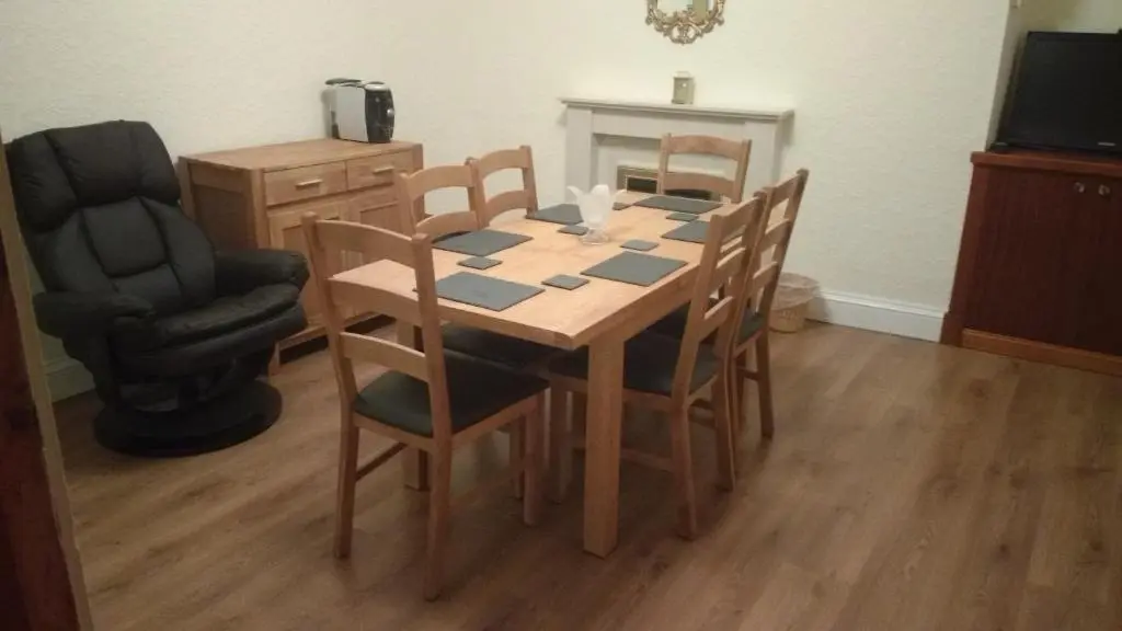 a dining room table and chairs with a television and a chair at Inveravon Holiday Home in Dufftown