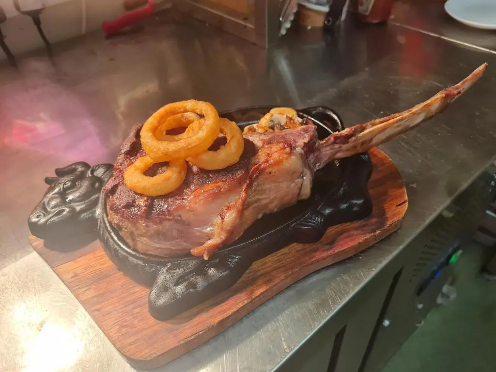 a piece of meat on a cutting board with onion rings at Victoria Hotel in Portknockie