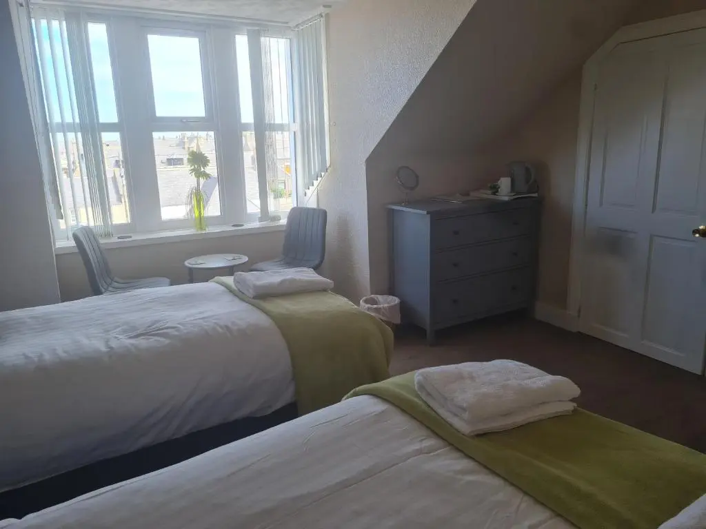 a bedroom with two beds and a dresser and a window at Victoria Hotel in Portknockie
