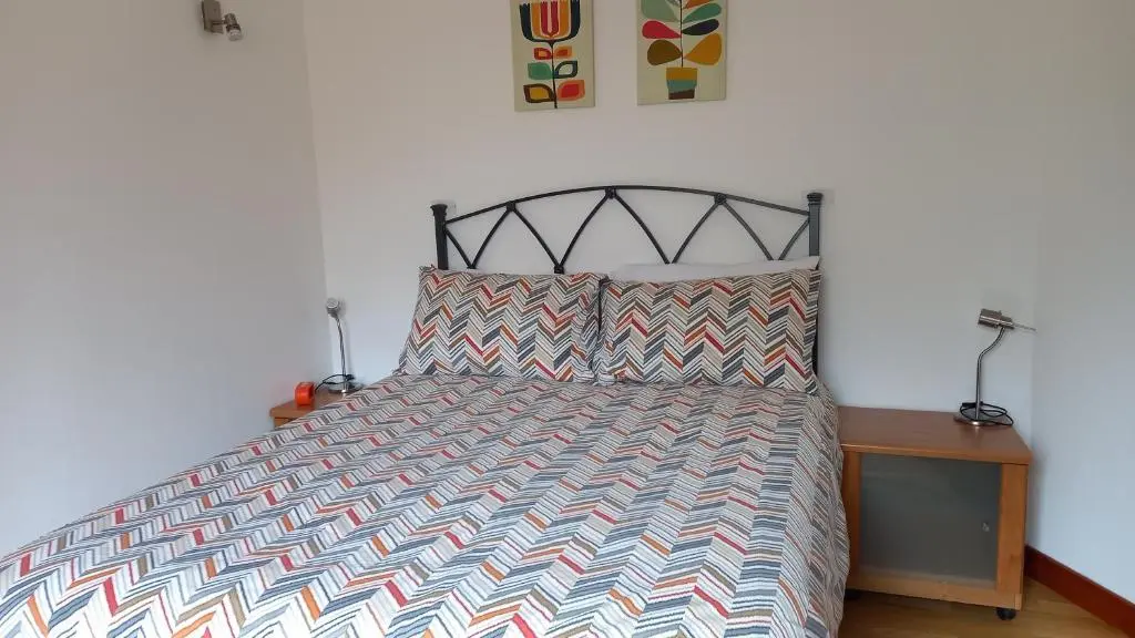 a bedroom with a bed with a black and white bedspread at North End The Cottage in Nairn