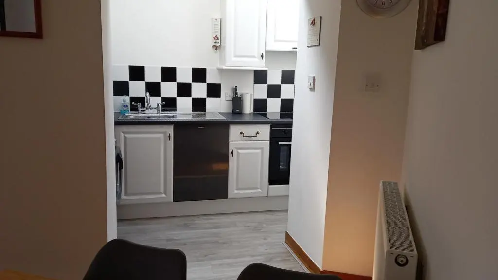a kitchen with a black and white checkered wall at North End The Cottage in Nairn