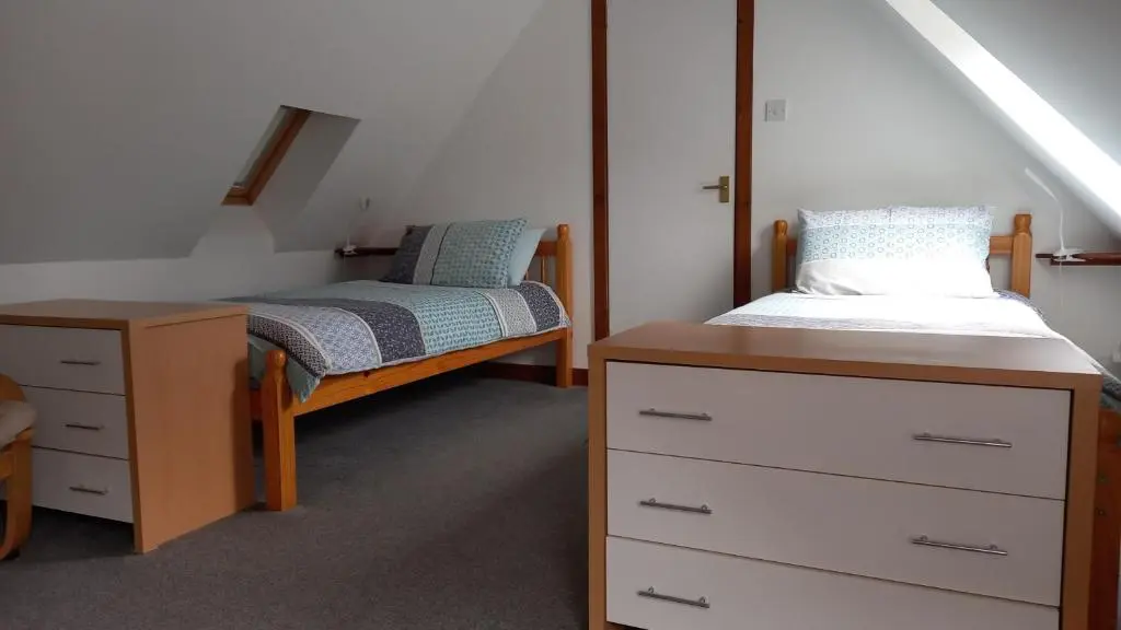 a bedroom with two twin beds and a dresser at North End The Cottage in Nairn