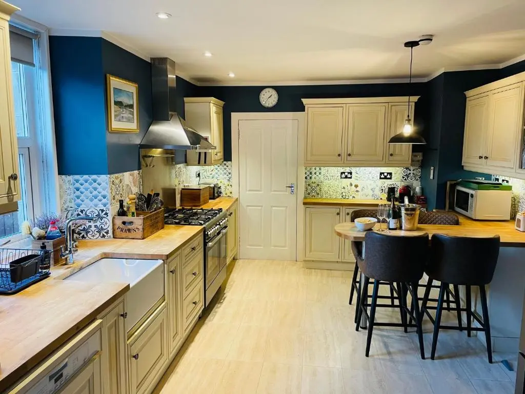 a kitchen with white cabinets and a table with chairs at Lairds Lodge Inverness in Inverness