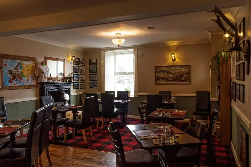 a restaurant with tables and chairs and a fireplace at Bannockburn Inn in Helmsdale