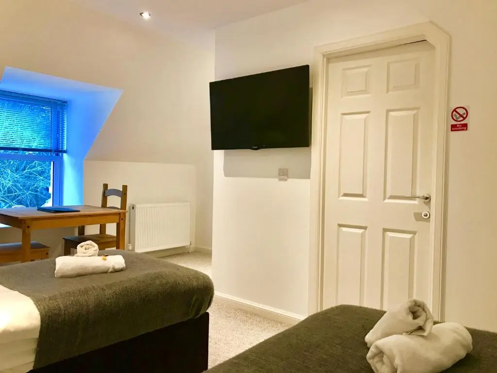 a bedroom with two beds and a flat screen tv at Drumdevan Country House in Inverness