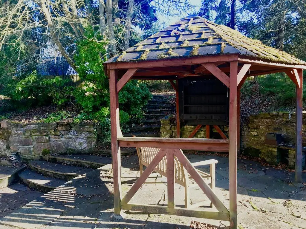a wooden gazebo with a chair in a garden at Drumdevan Country House in Inverness