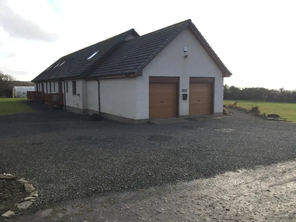a white building with two garage doors on a driveway at Acarsaid B&B in Lybster