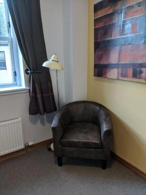 a chair sitting in a corner next to a window at Black Isle Bar & Rooms in Inverness