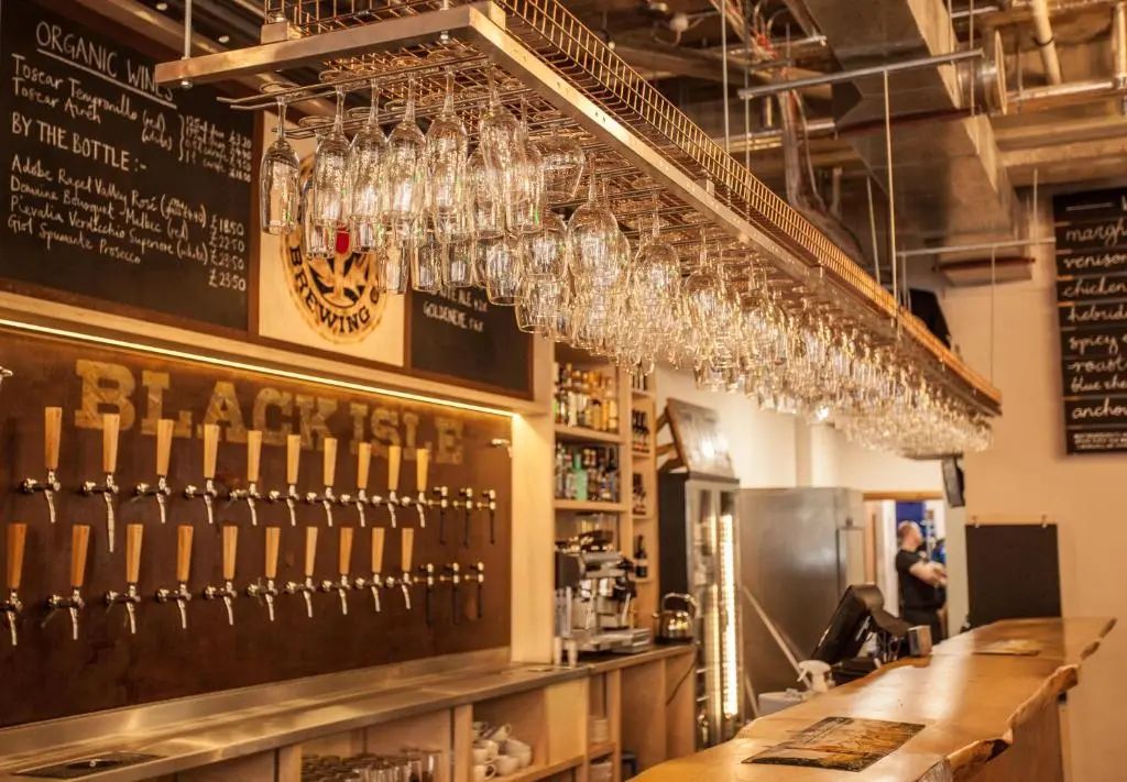 a bar with wine glasses hanging from the ceiling at Black Isle Bar & Rooms in Inverness