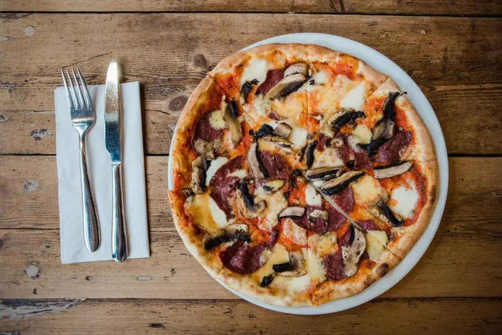 a pizza on a plate on a table with a fork and knife at Black Isle Bar & Rooms in Inverness