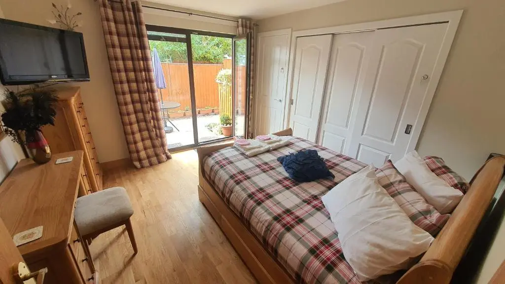 a bedroom with a bed and a tv and a window at Cosy Ness Escape, 16B Ardconnel Street in Inverness