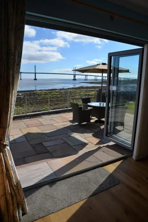 a patio with a view of the ocean through a window at Tangle Tower in Inverness
