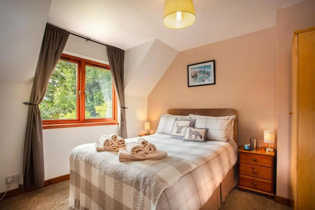 a bedroom with a bed with towels on it at Beechwood Lodge in Alness