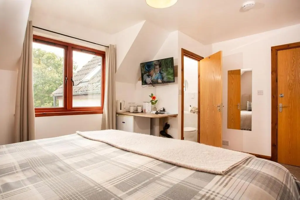 a bedroom with a bed and a window at Beechwood Lodge in Alness