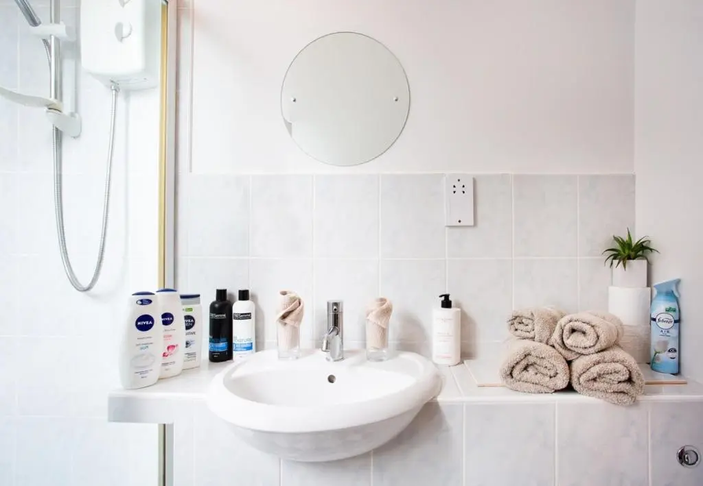 a bathroom with a sink and a mirror and towels at Beechwood Lodge in Alness
