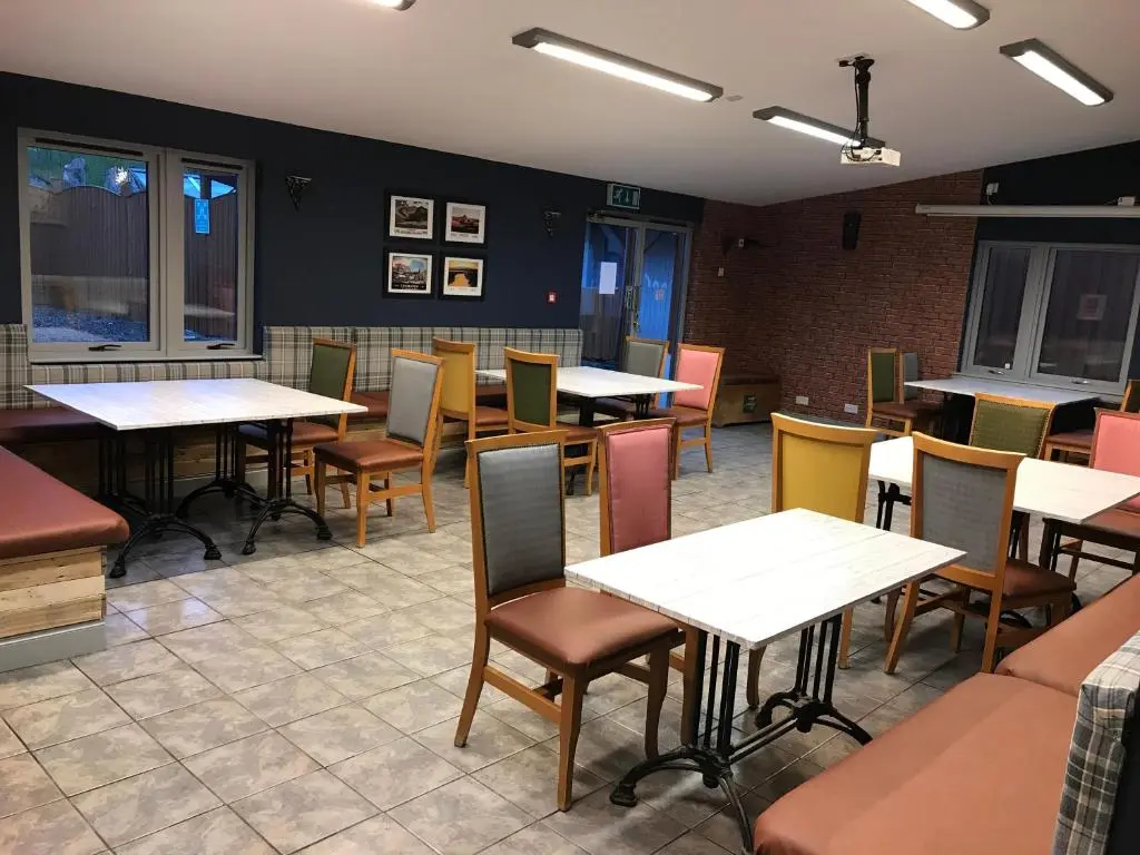 a restaurant with tables and chairs in a room at Loch Ness Backpackers Lodge in Drumnadrochit