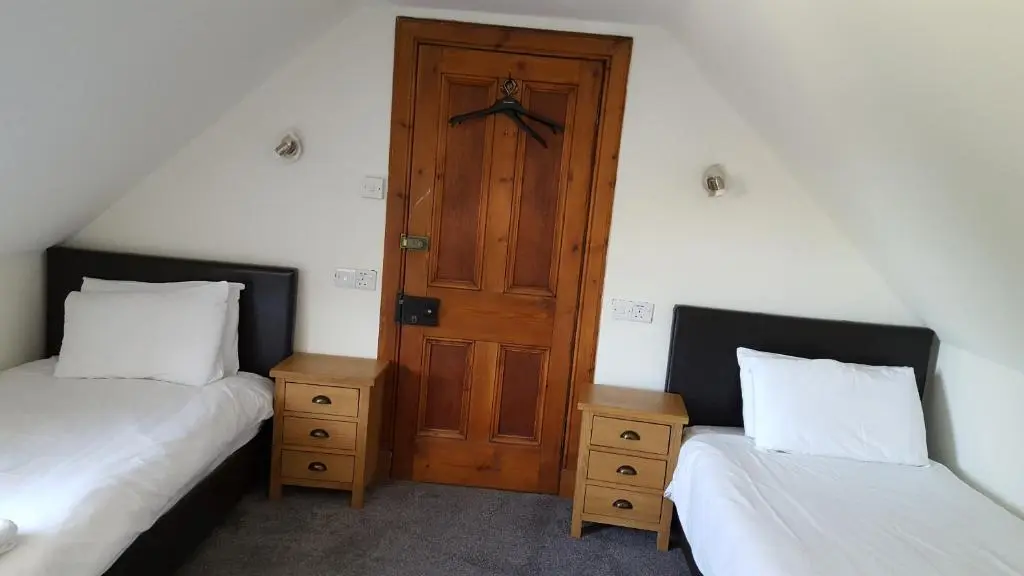 a room with two beds and a wooden door at Dunskaith Villa in Inverness