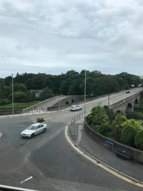 a white car driving down a road with a bridge at Buchan Hotel in Ellon