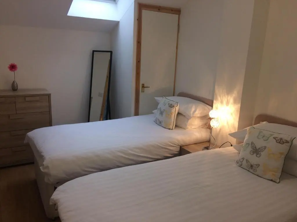 a hotel room with two beds and a mirror at Eastgate Apartment in Inverness