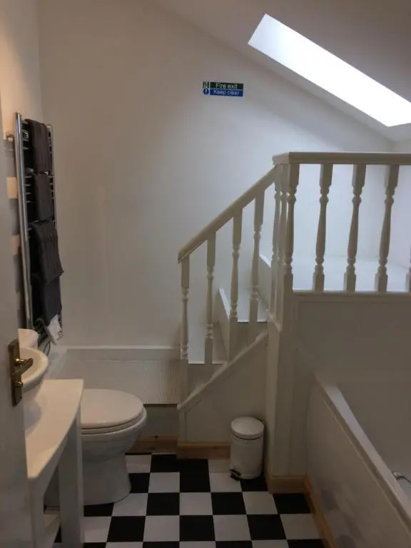 a bathroom with a toilet and a sink and stairs at Eastgate Apartment in Inverness