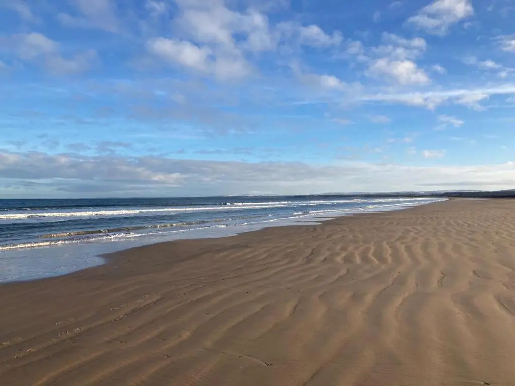 a sandy beach with waves in the ocean at Luxury Apartment at Barron House in Nairn