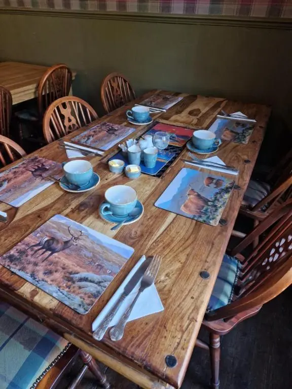 a wooden table with plates and napkins on it at Strathardle Lodge in Kirkmichael
