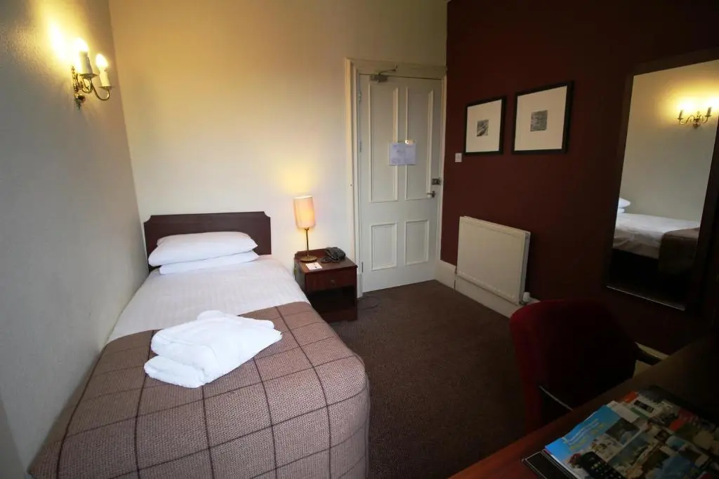 a hotel room with a bed and a mirror at Ben Wyvis Hotel in Strathpeffer