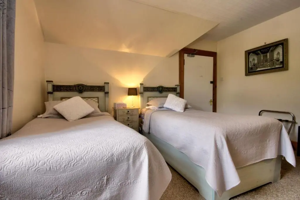 a bedroom with two beds with white sheets at Glasdair in Inverness