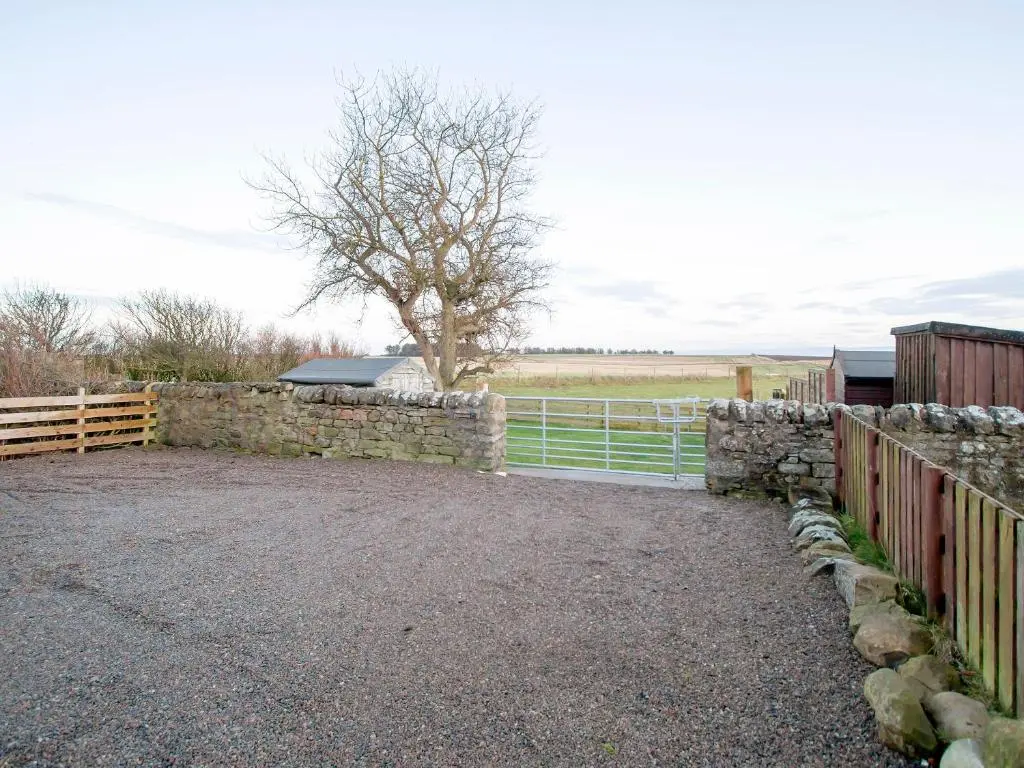 a stone fence with a gate and a tree at The Paddock in Portmahomack