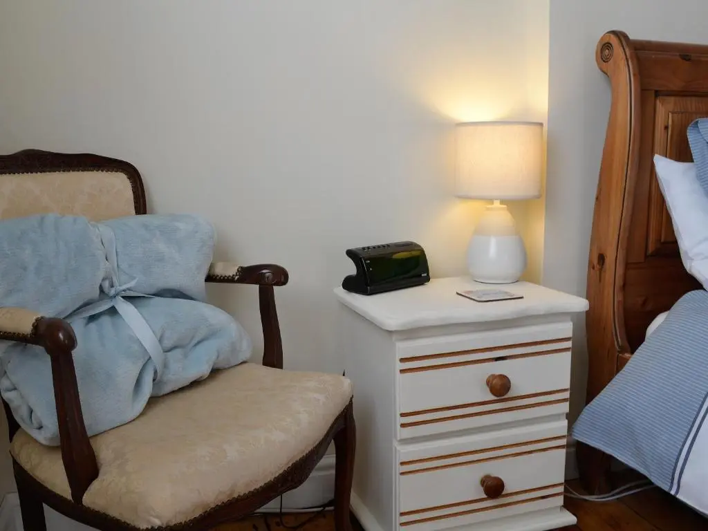 a bedroom with a bed and a chair and a nightstand at Salty Dog in Findochty