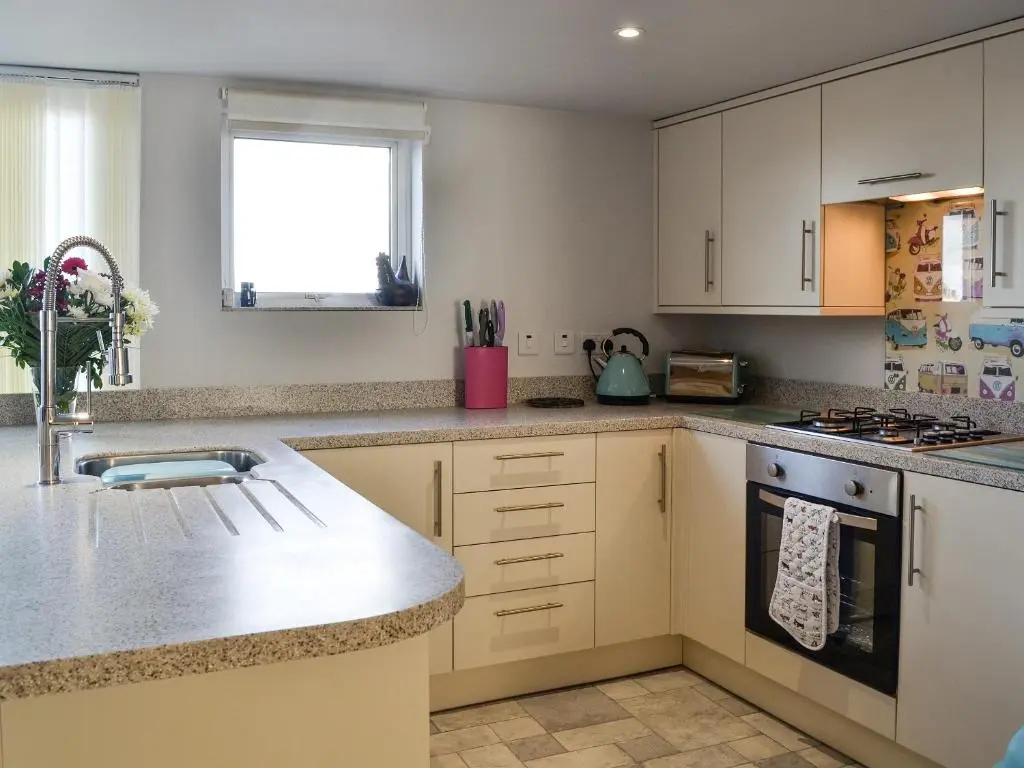 a kitchen with white cabinets and a sink at Salty Dog in Findochty