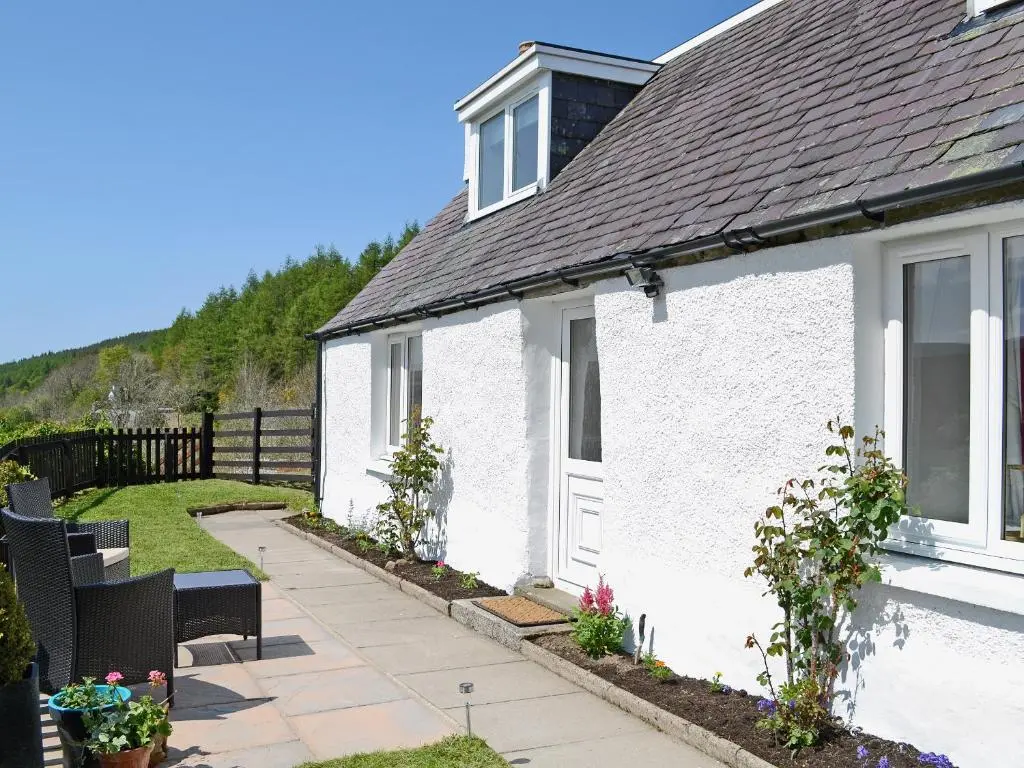 a white house with a porch and a patio at The Wee Hoose in Achnahanat