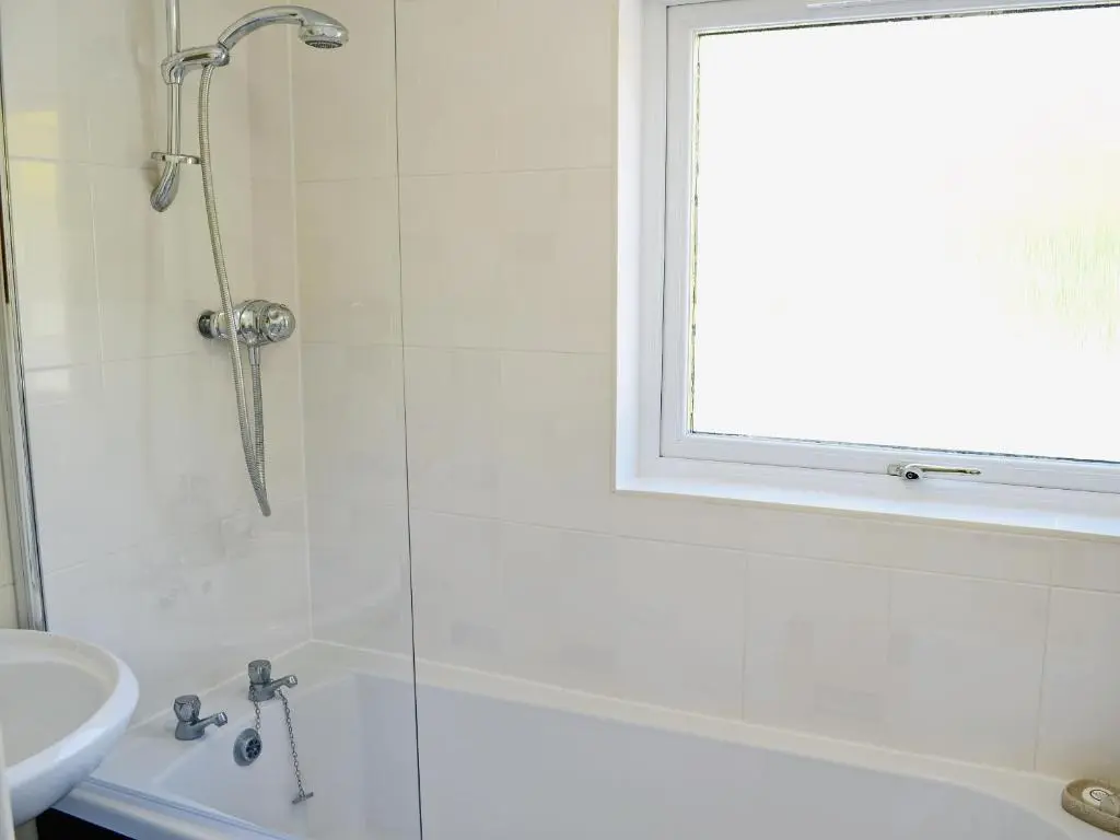 a bathroom with a shower and a sink at The Wee Hoose in Achnahanat