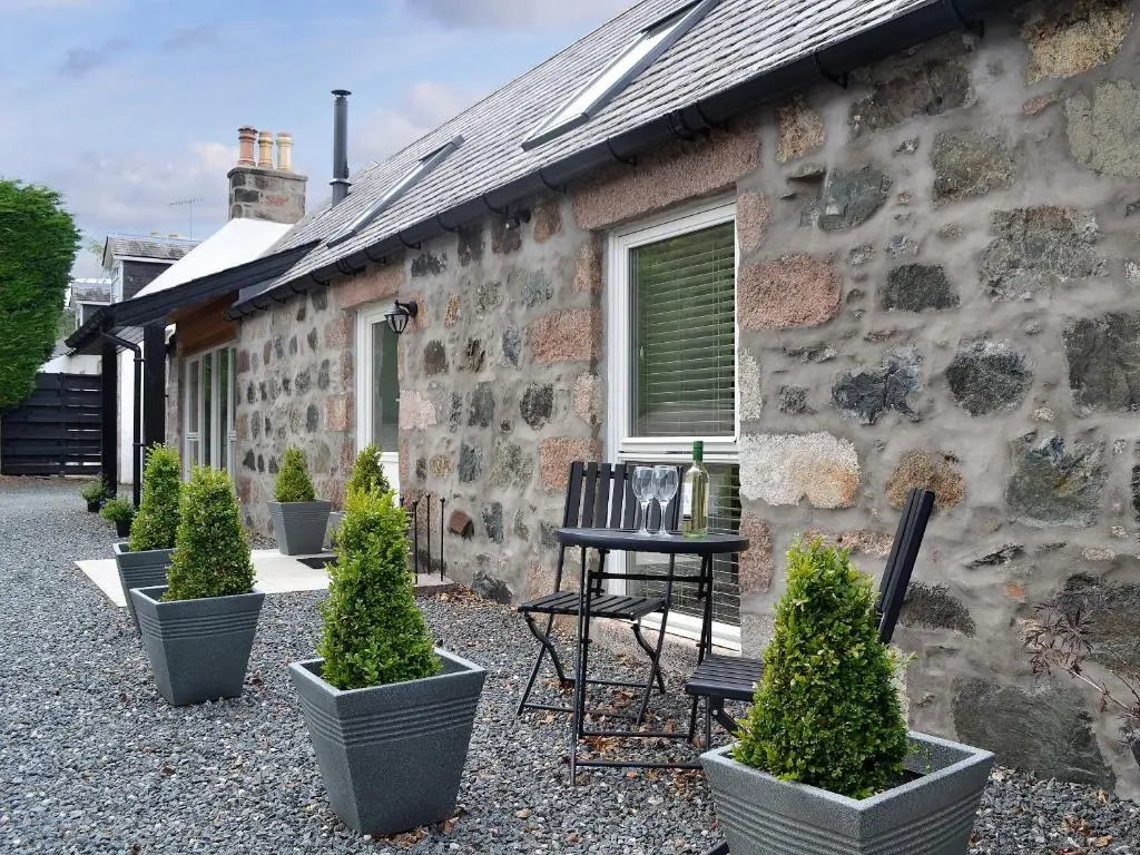 a stone house with a table and chairs in front of it at Longcroft Dairy in Oyne