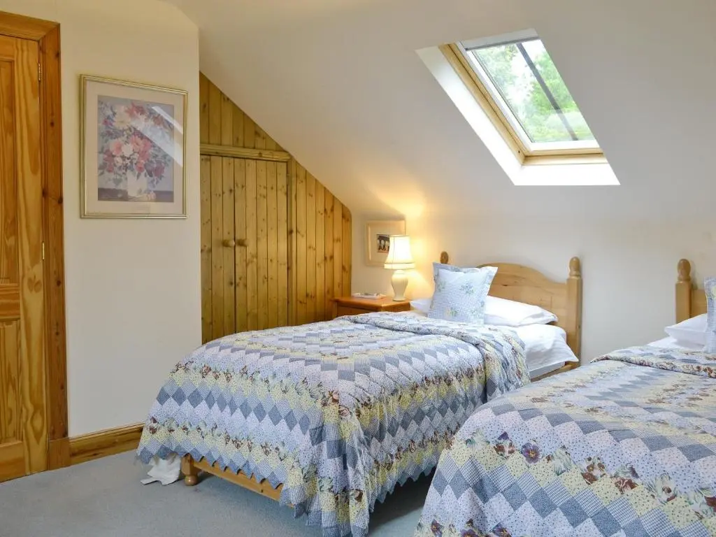 a attic bedroom with two beds and a window at Little Blackhall Lodge in Banchory