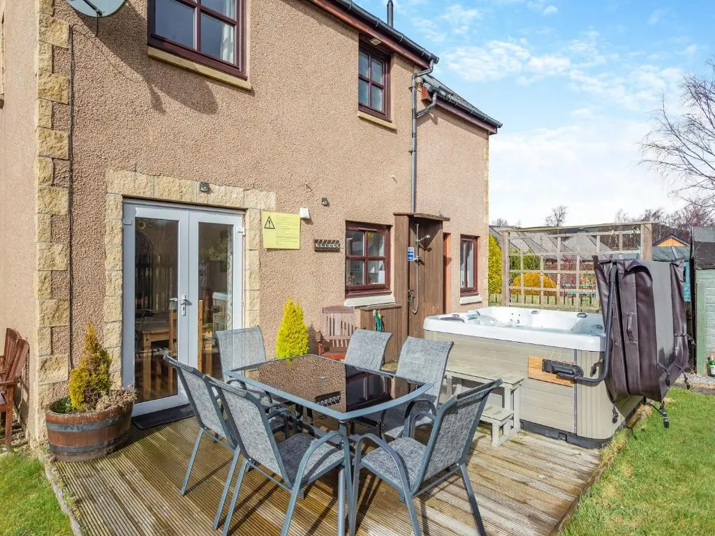 a patio with a table and chairs on a deck at Cairnie View in Aviemore