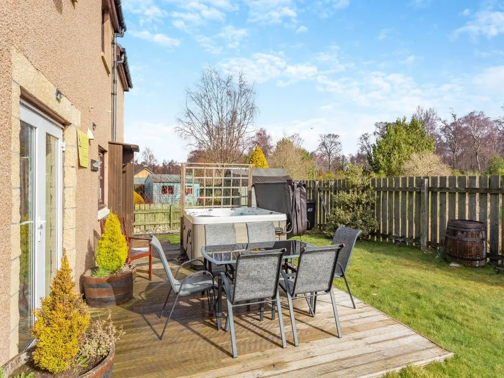 a backyard with a table and chairs on a deck at Cairnie View in Aviemore