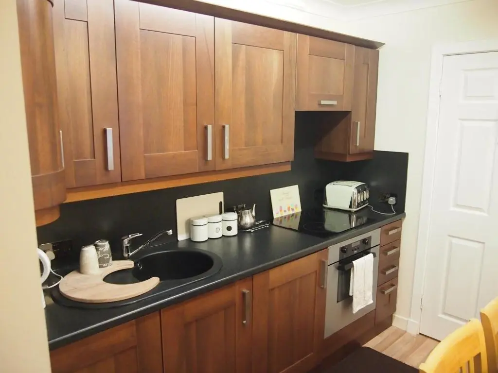 a kitchen with a sink and wooden cabinets at Craignay Guest House in Inverness